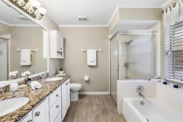 a bathroom with a granite countertop double vanity sink a mirror and a bathtub