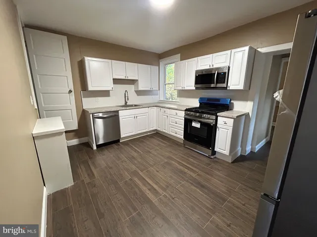 a kitchen with granite countertop a stove top oven a sink dishwasher and a refrigerator with wooden floor