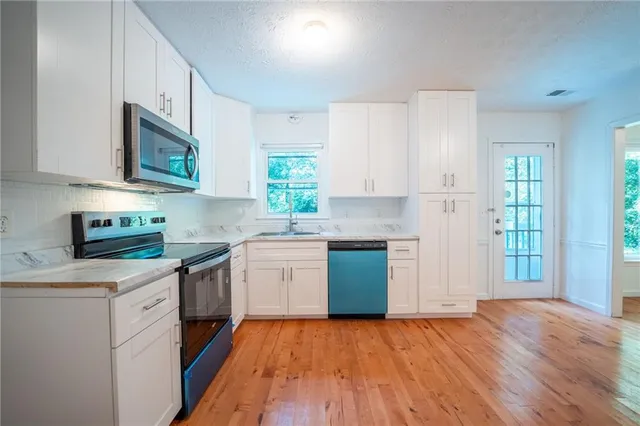 a kitchen with stainless steel appliances granite countertop a sink a stove top oven a refrigerator with wooden floors and cabinets