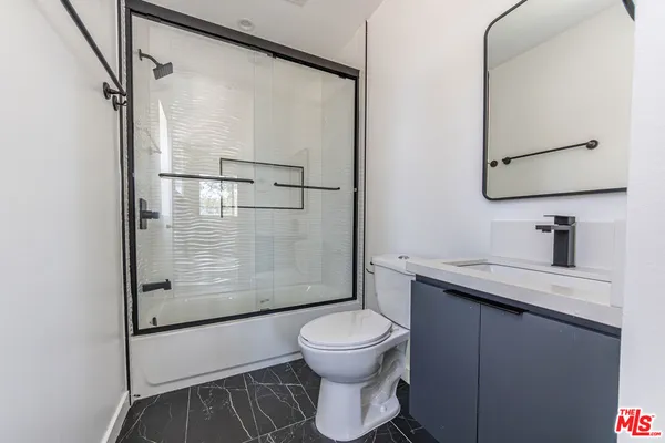 a bathroom with a granite countertop sink toilet a mirror and shower