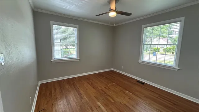 a view of empty room with wooden floor and fan
