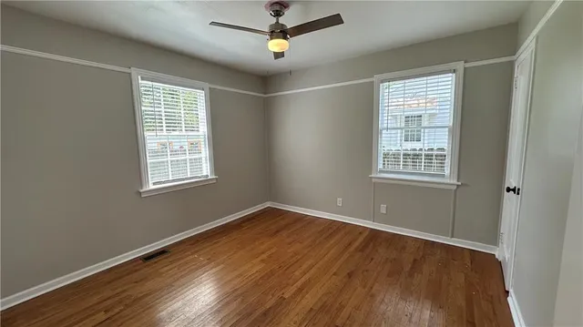 a view of empty room with wooden floor and fan