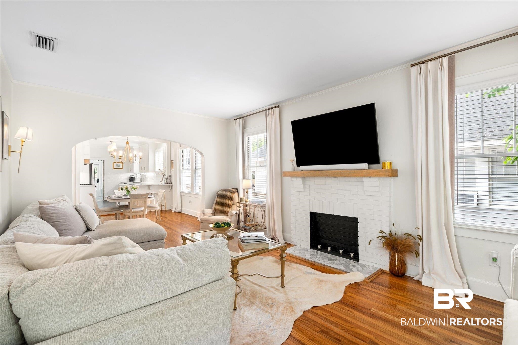 112 Crenshaw Street Mobile, AL 36606 - Photo 5 of 21 Living area featuring visible vents, arched walkways, an inviting chandelier, a fireplace, and wood finished floors