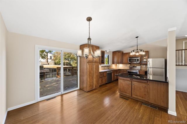 a kitchen with stainless steel appliances granite countertop a refrigerator a stove top oven and wooden floors