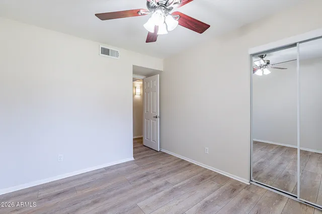 an empty room with wooden floor closet and windows