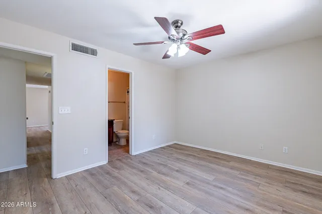 an empty room with wooden floor closet and windows