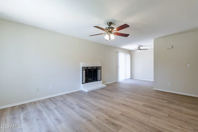 a view of empty room with wooden floor and ceiling fan