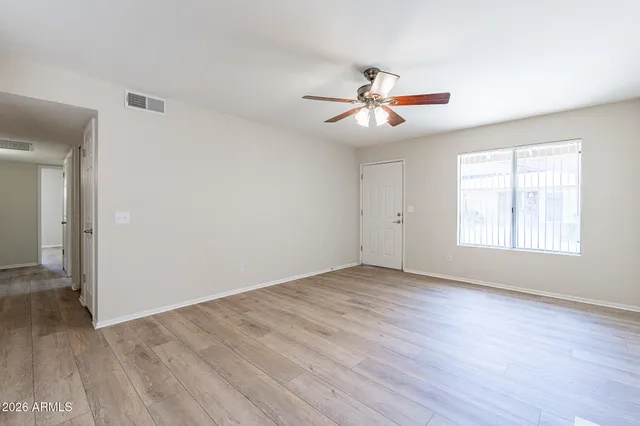 a view of empty room with wooden floor and fan