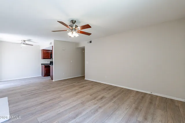 a view of empty room with wooden floor and ceiling fan