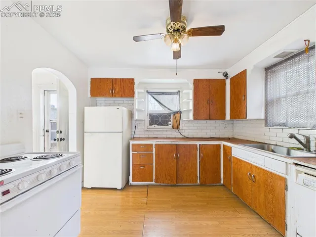 a kitchen with stainless steel appliances granite countertop a sink a stove a refrigerator a washer dryer and white cabinets