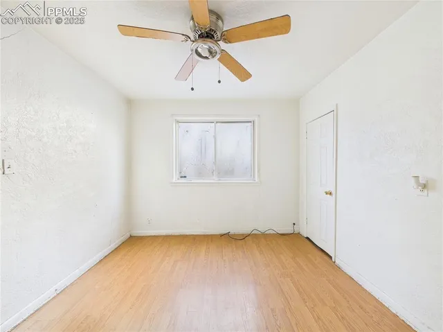 an empty room with a window and a ceiling fan