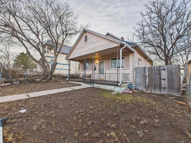 a view of a house with a large tree and wooden fence