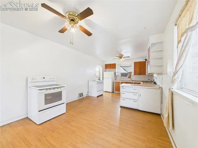 a kitchen with stainless steel appliances a stove top oven cabinets a window and a couch
