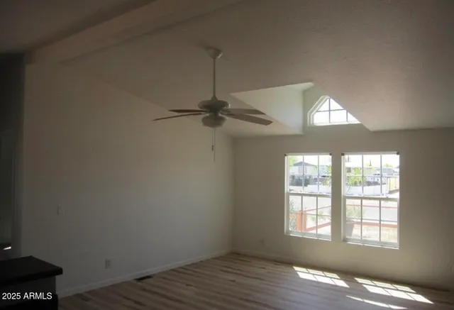 an empty room with wooden floor cabinet and windows