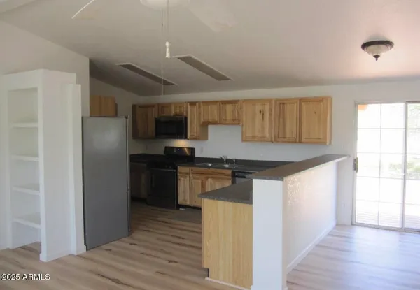 a kitchen with stainless steel appliances granite countertop a refrigerator a sink dishwasher a stove with wooden cabinets and wooden floor