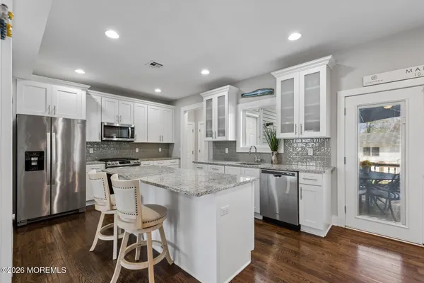 a kitchen with stainless steel appliances granite countertop a refrigerator a stove a sink a dining table and chairs
