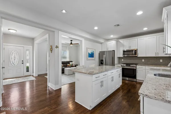 a large kitchen with stainless steel appliances granite countertop a lot of counter space and wooden floors