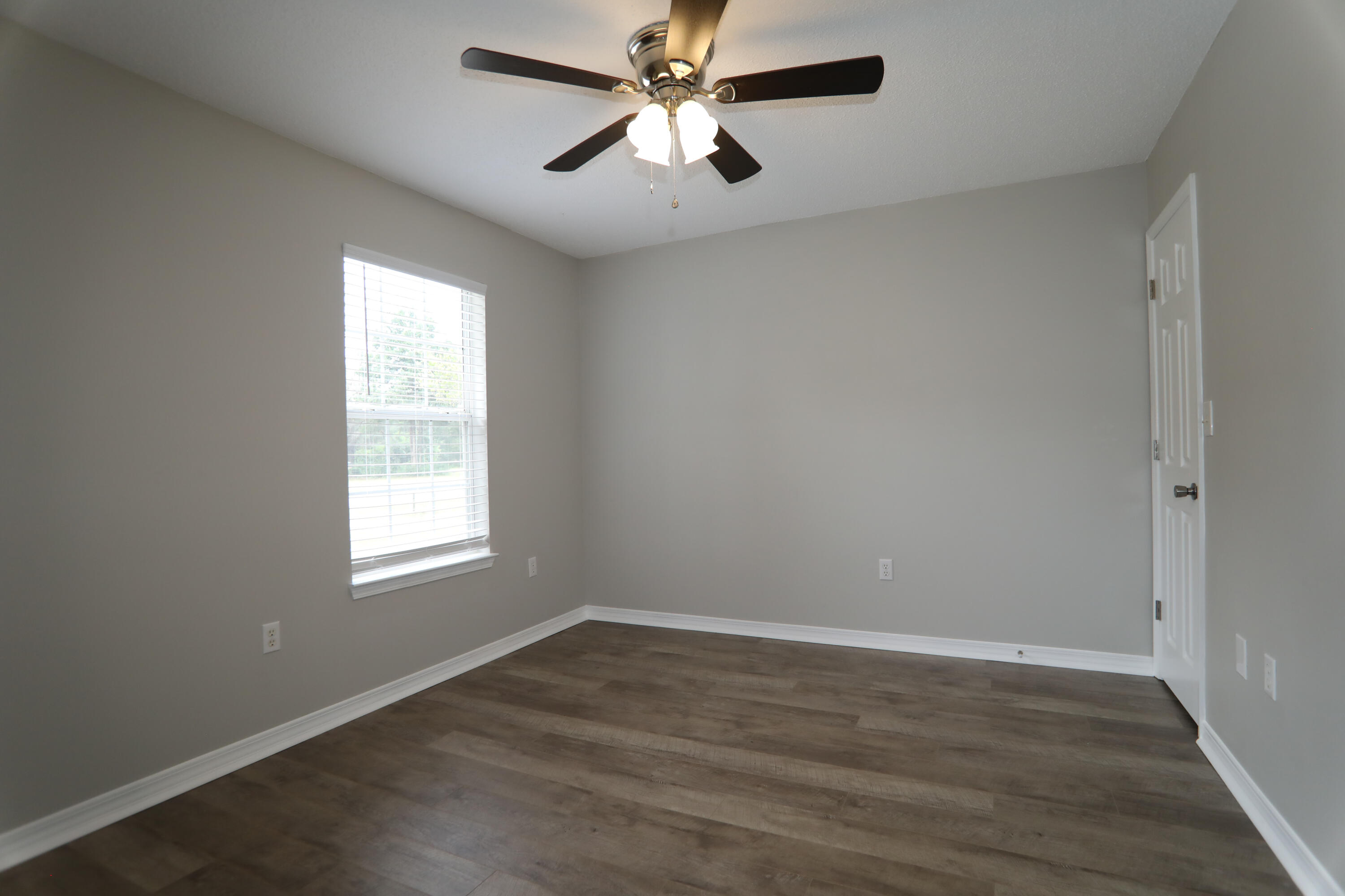 159 Patch Avenue Crestview, FL 32539 - Photo 5 of 11 an empty room with wooden floor ceiling fan and windows