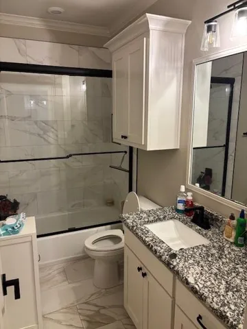 a bathroom with a granite countertop sink a toilet a mirror and vanity