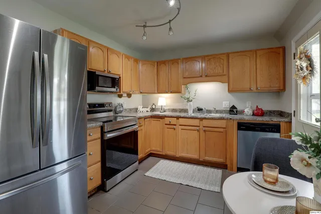 a kitchen with granite countertop stainless steel appliances a sink stove refrigerator and cabinets