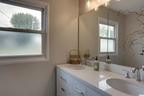 a bathroom with a double vanity sink window and mirror