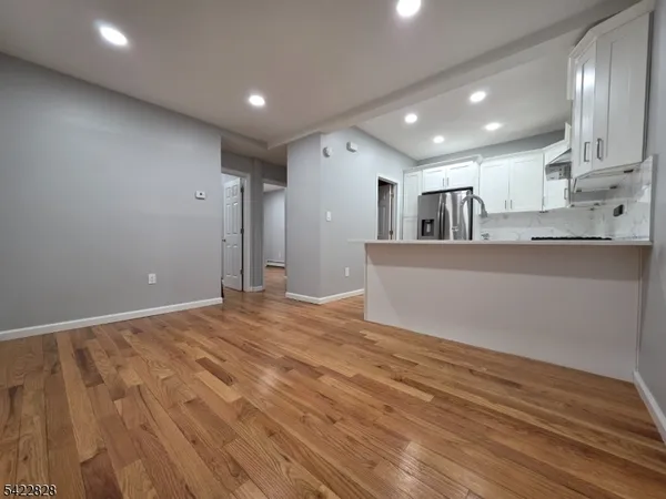 a view of a kitchen with kitchen island a sink wooden floor and a refrigerator