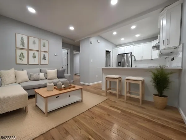 a living room with furniture a wooden floor and kitchen view