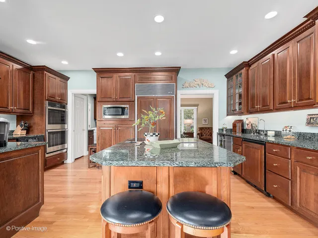 a kitchen with stainless steel appliances granite countertop a stove a sink a microwave a refrigerator and cabinets