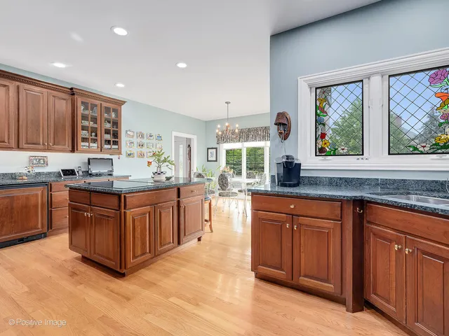 a kitchen with stainless steel appliances granite countertop wooden cabinets a stove a sink and a large window