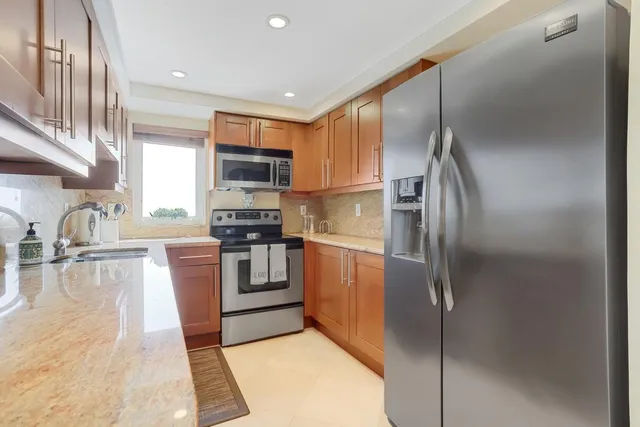 a kitchen with stainless steel appliances granite countertop a refrigerator a stove and a sink with wooden floor