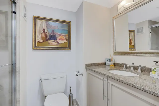 a bathroom with a granite countertop toilet a sink and mirror