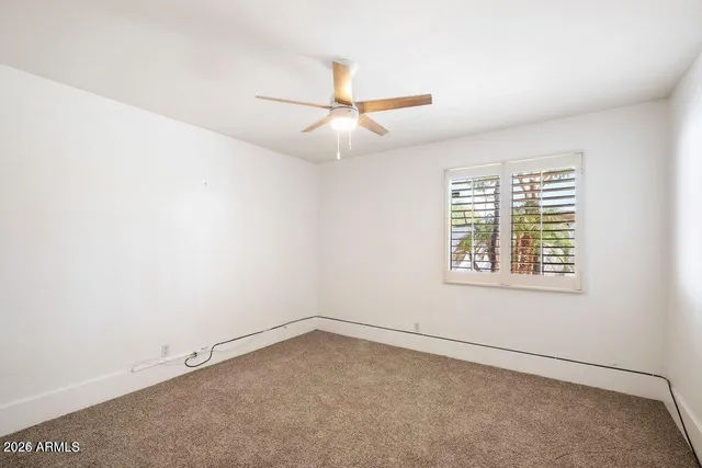 an empty room with a window and a fan
