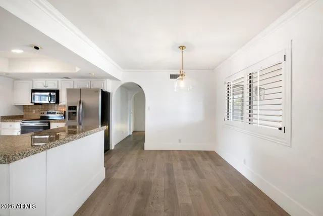 a view of a kitchen with kitchen island a sink wooden floor and stainless steel appliances