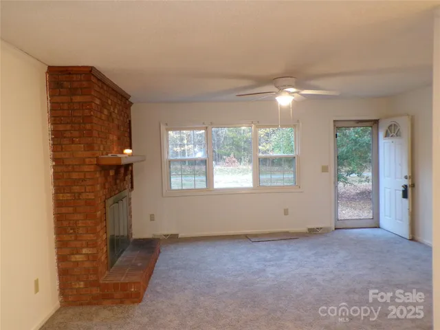a view of an empty room with a fireplace and a window