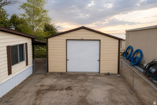 305 West Elmo Road Elmo, UT 84521 - Photo 24 of 27 Detached garage with a roll-up door, corrugated siding, and a brown trim roof