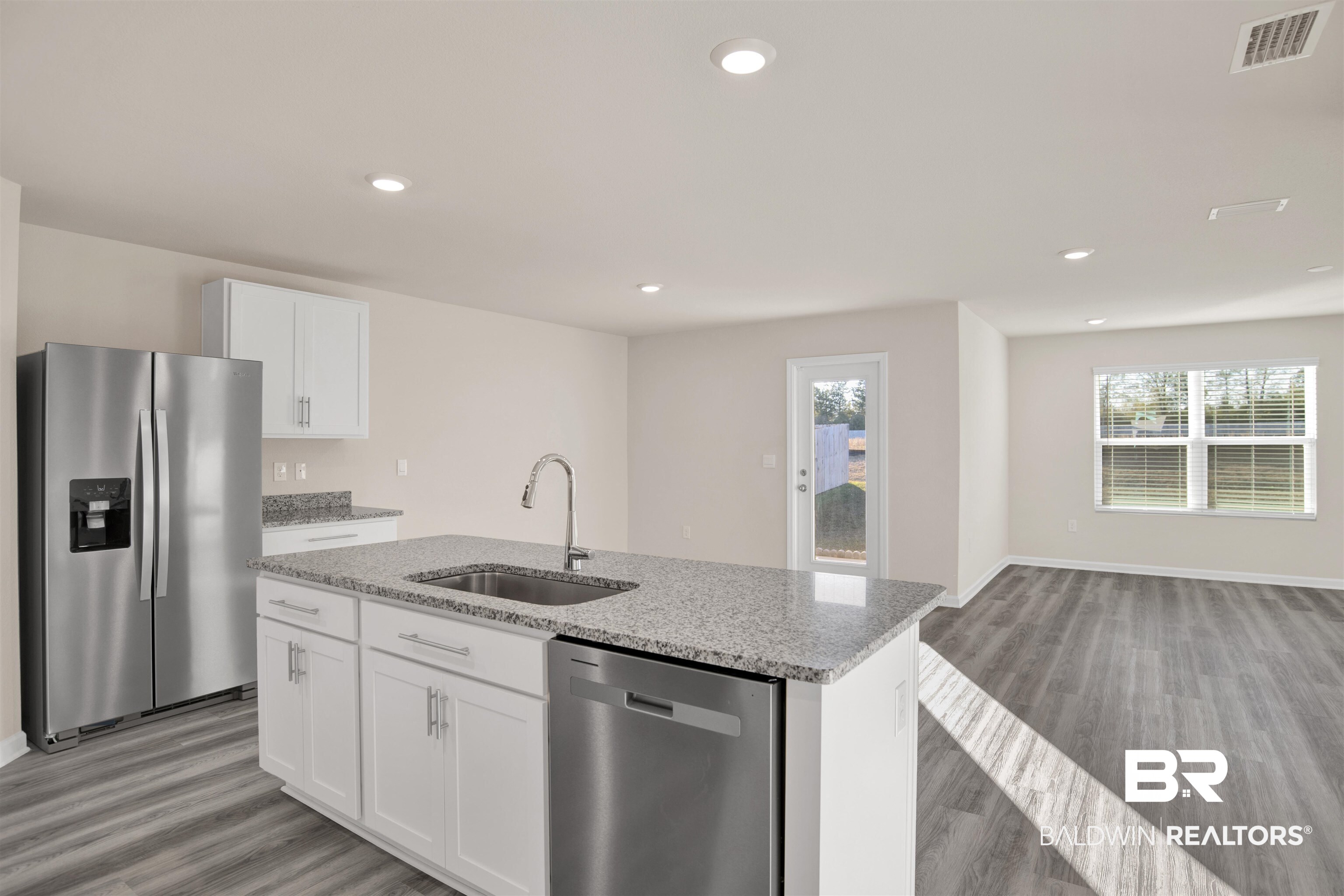 32038 Lyon Road Daphne, AL 36527 - Photo 30 of 30 Kitchen featuring appliances with stainless steel finishes, white cabinets, light stone counters, light wood-style floors, and open floor plan