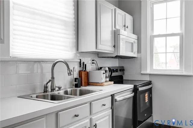 a kitchen with stainless steel appliances granite countertop a sink a window and cabinets