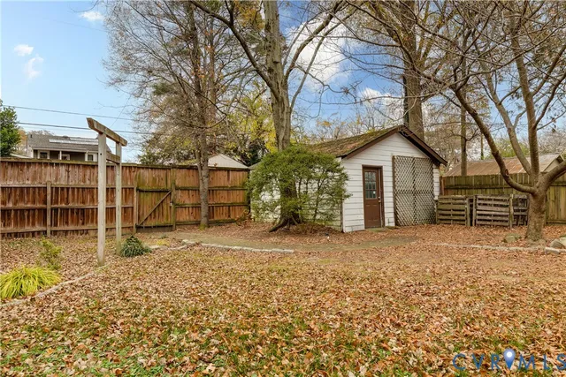 a view of a house with a large tree and wooden fence