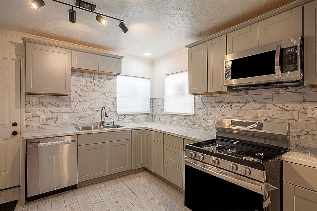 a kitchen with stainless steel appliances a sink a stove and cabinets