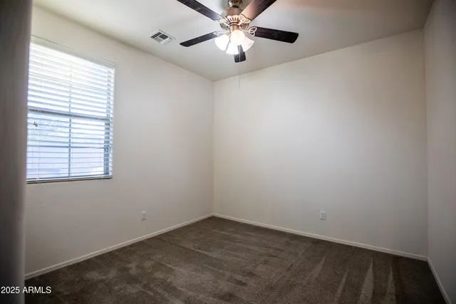 an empty room with a window and a fan