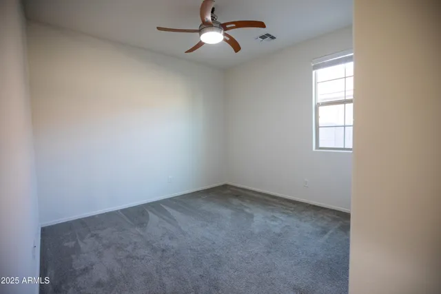 an empty room with windows and fan