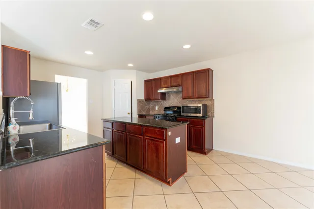 a large kitchen with stainless steel appliances granite countertop a sink and a refrigerator