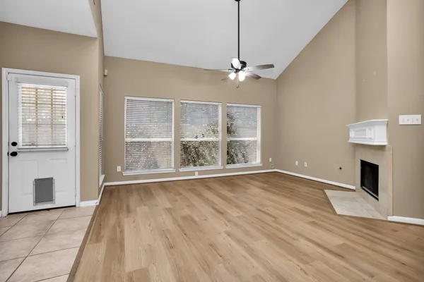 a view of an empty room with wooden floor fireplace and a window