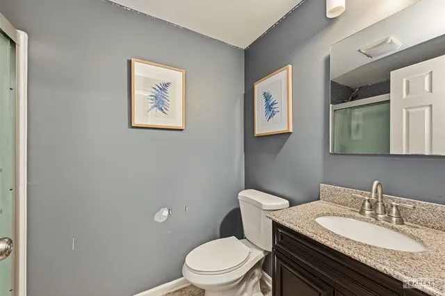 a bathroom with a granite countertop toilet a sink and a mirror