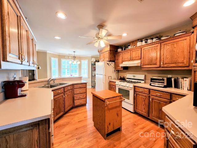 1405 Biggers Cemetery Road Monroe, NC 28110 - Photo 8 of 29 a kitchen with stainless steel appliances granite countertop a stove top oven a sink dishwasher a dining table and chairs with wooden cabinets