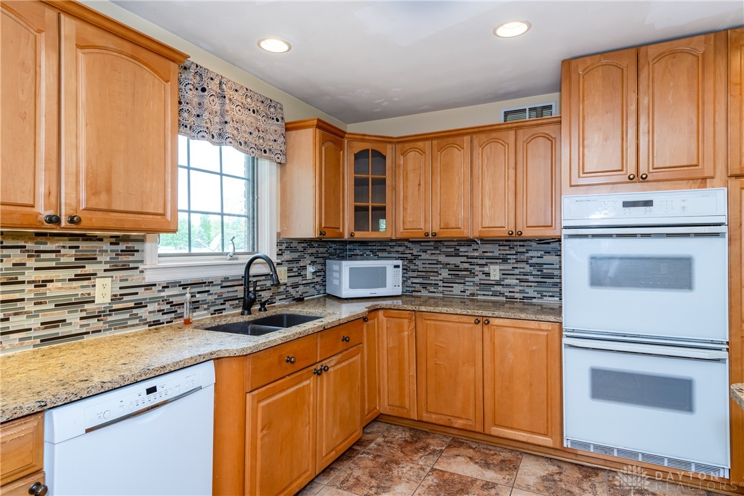 9981 Ridge Acres Lane Englewood, OH 45322 - Photo 16 of 73 This kitchen offers warm wood cabinetry, granite countertops, and modern appliances.