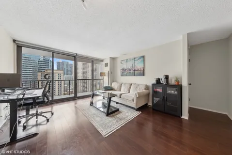a living room with furniture large window and wooden floor