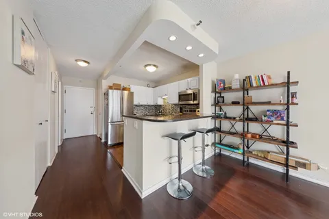 a kitchen with stainless steel appliances kitchen island granite countertop a refrigerator a stove and white cabinets with wooden floor