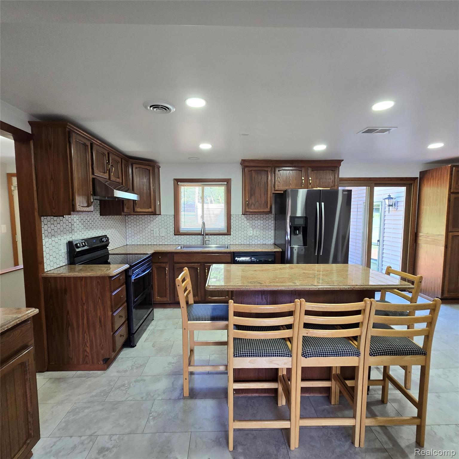 311 Nevada Avenue Rochester, MI 48309 - Photo 22 of 70 Kitchen featuring wood cabinetry, granite countertops, a hexagonal tile backsplash, stainless steel appliances, and a central island with seating
