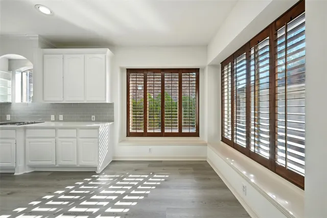 a view of an empty room with wooden floor fireplace and a window